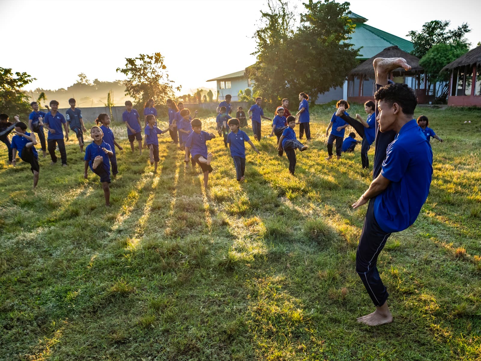 A teacher leading younger Hummingbird students through a kung-fu drill at golden hour